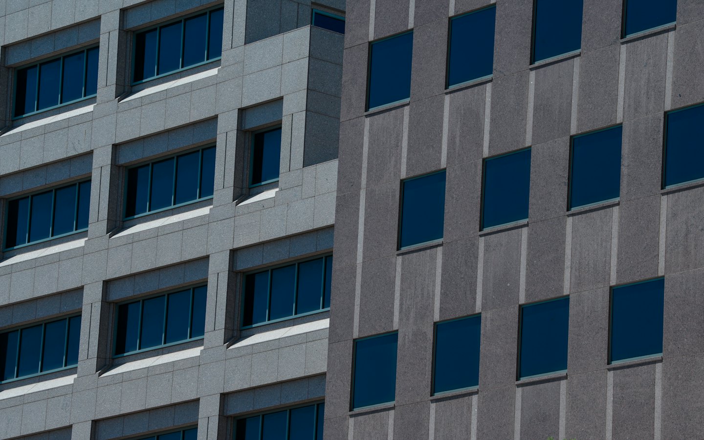 Two modern office buildings with contrasting facades stand side by side.